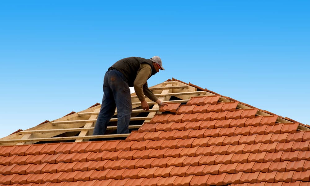 Professional roofer replacing flashing to fix a roof leak around a chimney.
