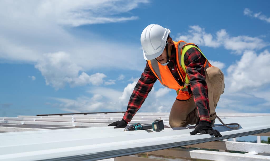 Applying protective coating on a metal roof to enhance durability, reduce heat absorption, and protect against rust and water damage.