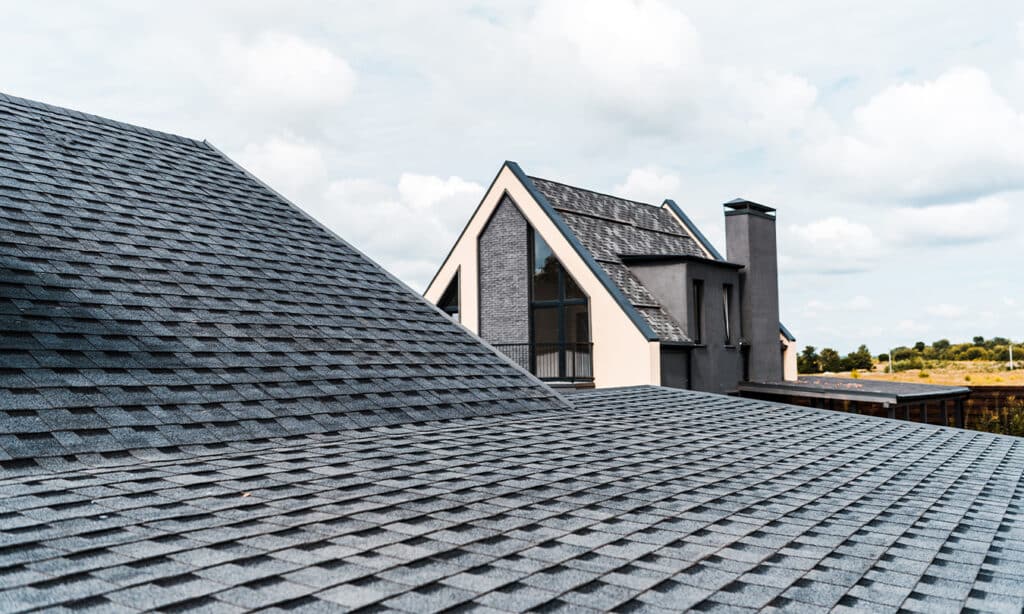 Close-up of asphalt shingle roof construction, showcasing the layers, colors, and durability of shingle roofing.