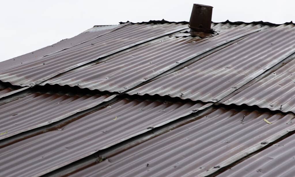 Early signs of metal roof damage, including rust spots, loose screws, and peeling paint, indicating the need for timely maintenance.