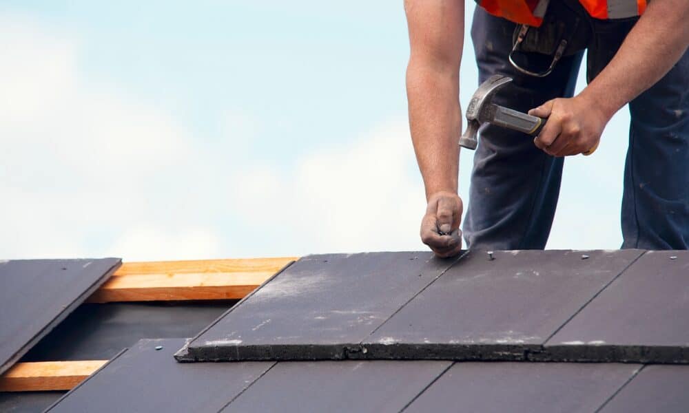 Applying roofing sealant to fix small roof leaks as a DIY solution.